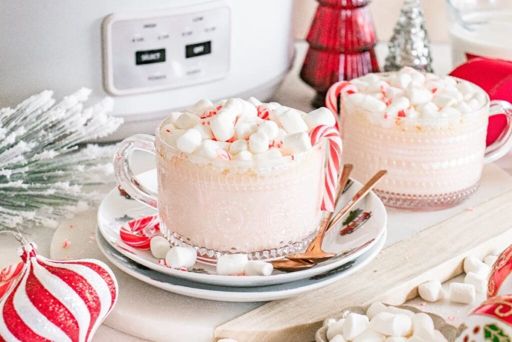 Clear mugs of white hot chocolate with marshmallows and candy canes.