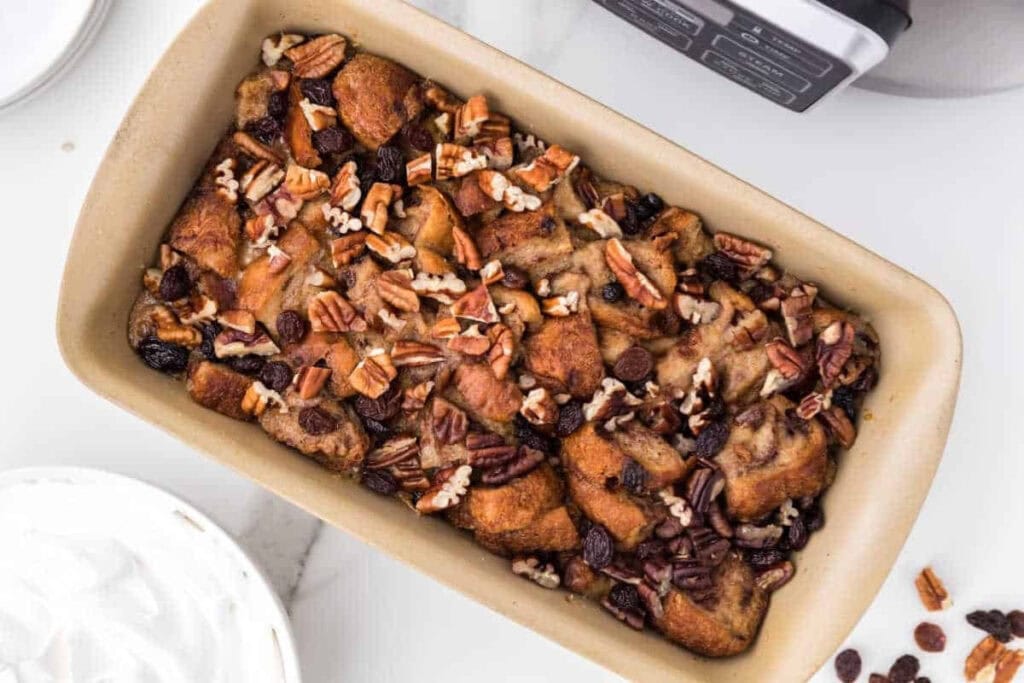 Baked bread pudding with pecans and raisins in a baking dish.