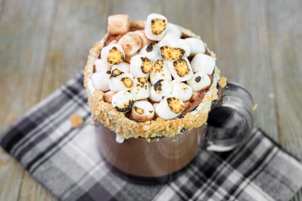 Hot chocolate with graham cracker rim and toasted marshmallows on top.