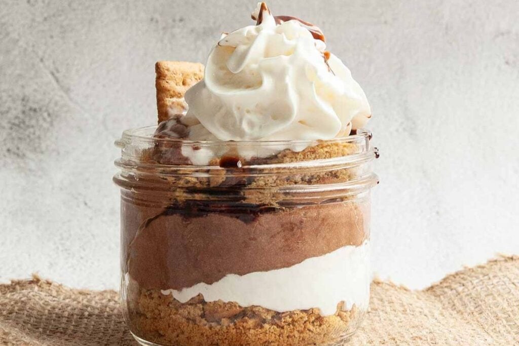 S'mores parfait in a jar with graham cracker, chocolate mousse, and whipped cream.