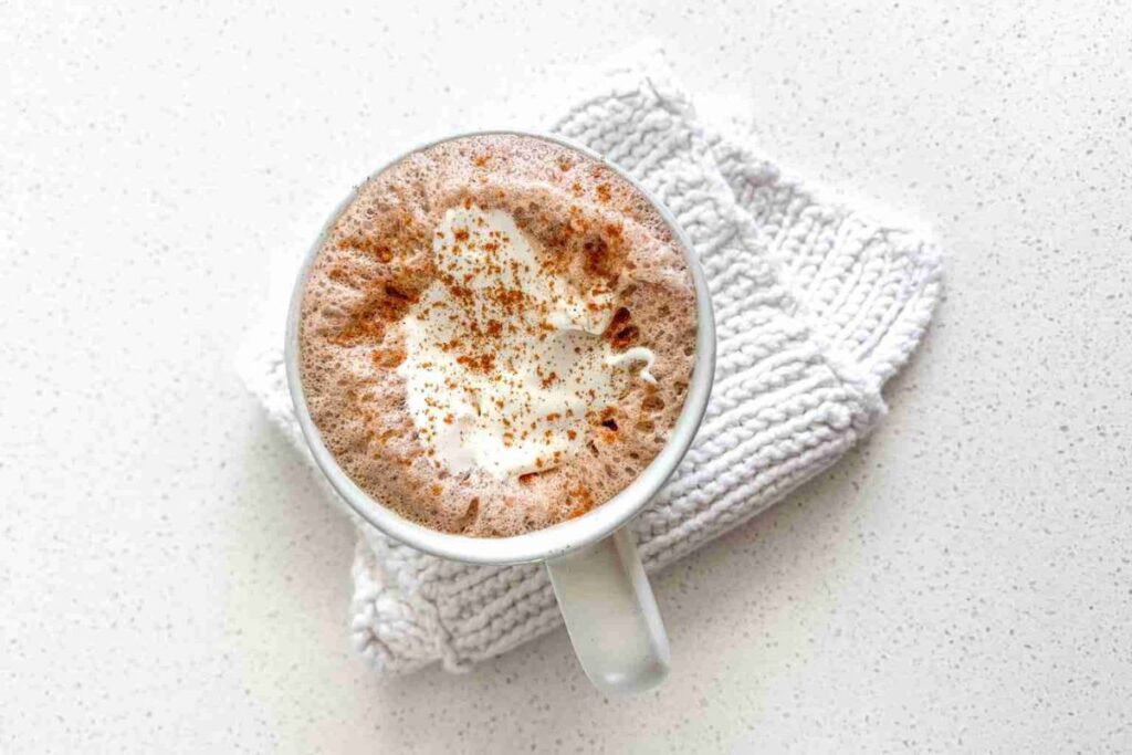 Overhead view of hot chocolate with whipped cream and cinnamon.