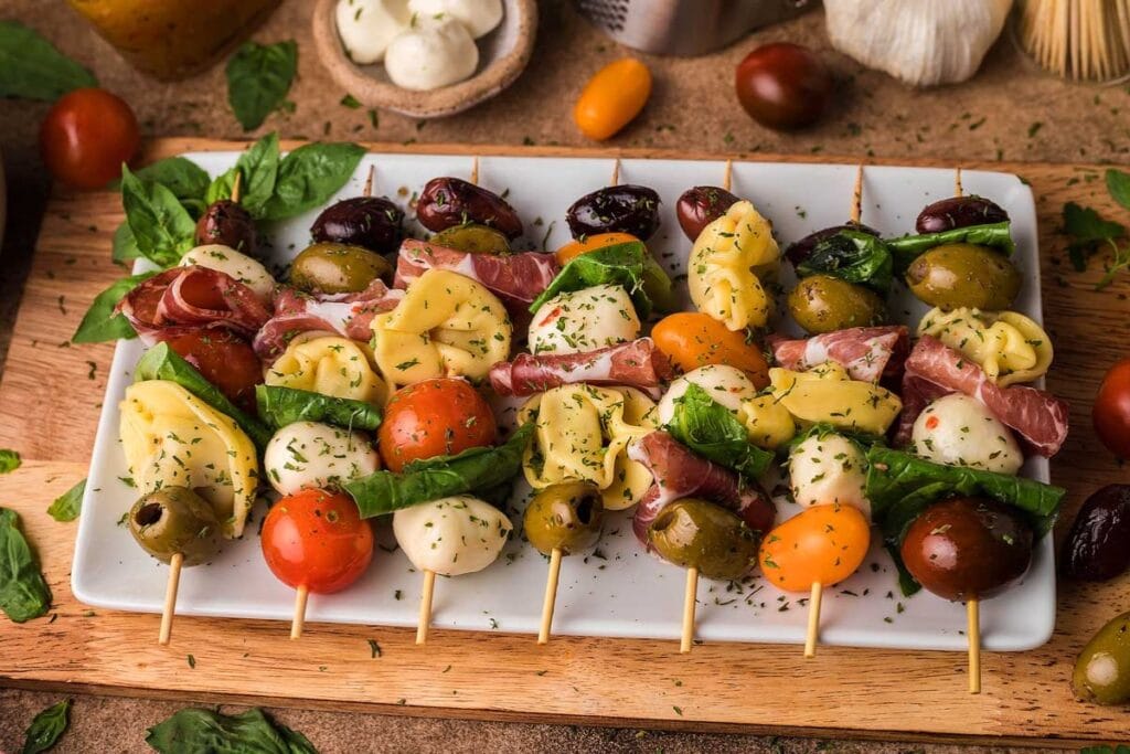 Colorful antipasto bites with cherry tomatoes, mozzarella, olives, and cured meats on skewers.