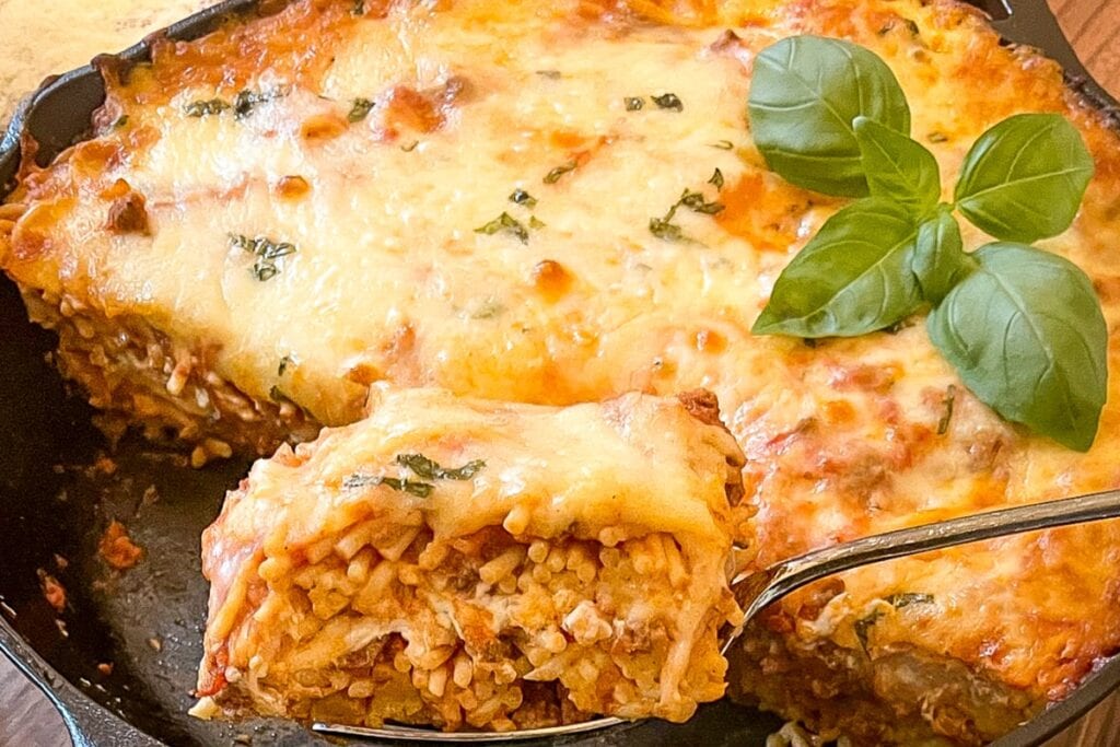 Baked spaghetti casserole on a spatula lifted from a skillet.