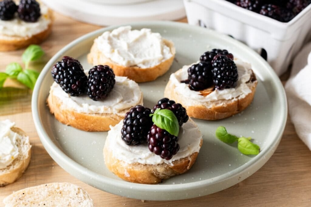 Blackberry balsamic whipped goat cheese crostini on a plate.