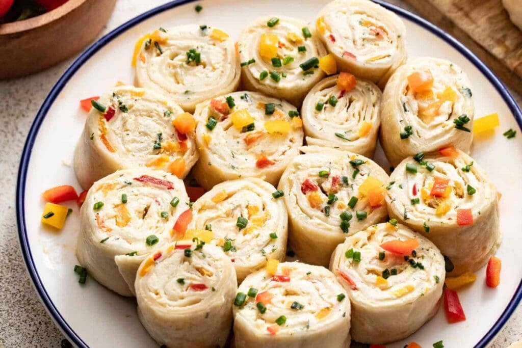 Cream cheese tortilla roll ups on a plate.