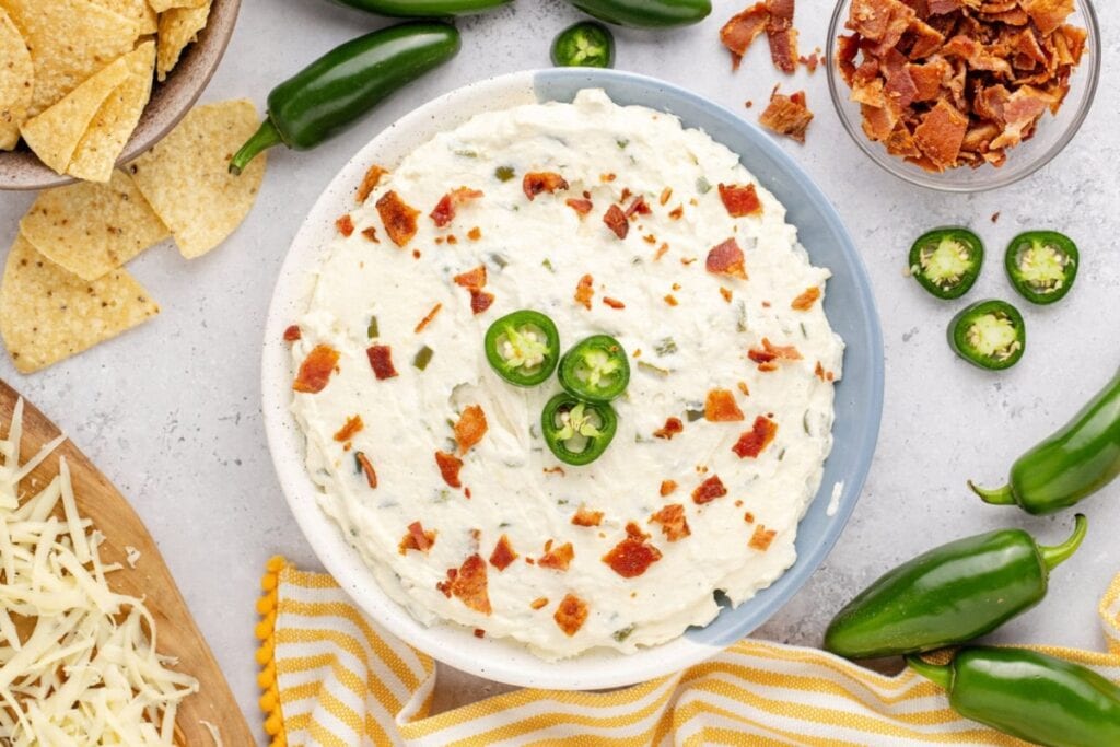 Creamy jalapeño popper dip in a bowl, topped with crispy bacon.