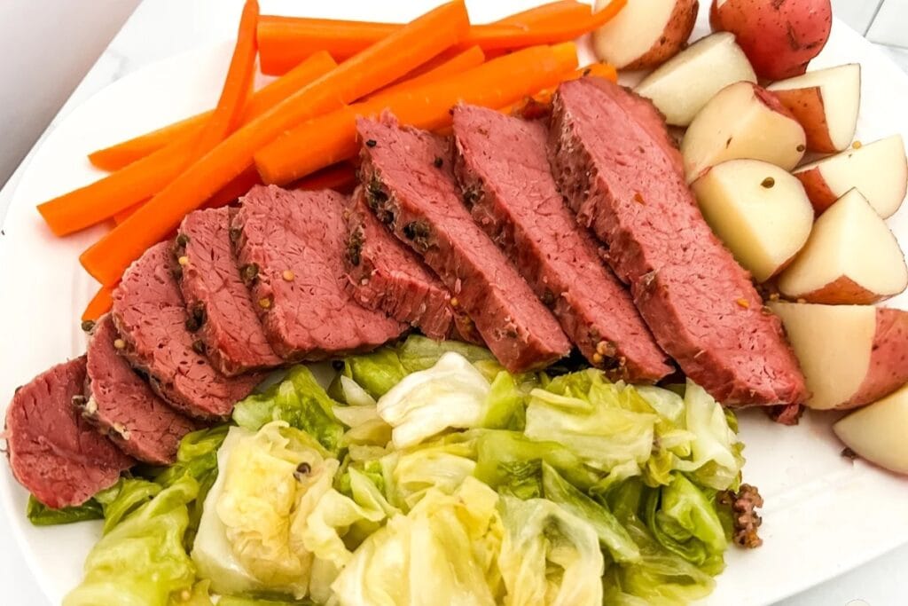 Sliced corned beef served on a plate with vegetables.