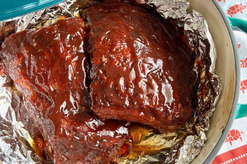 Dutch oven ribs in a baking dish with tender, saucy meat.