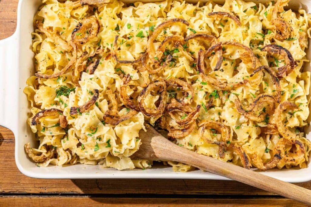 French Onion Noodle Casserole in a baking dish with a wooden spoon.