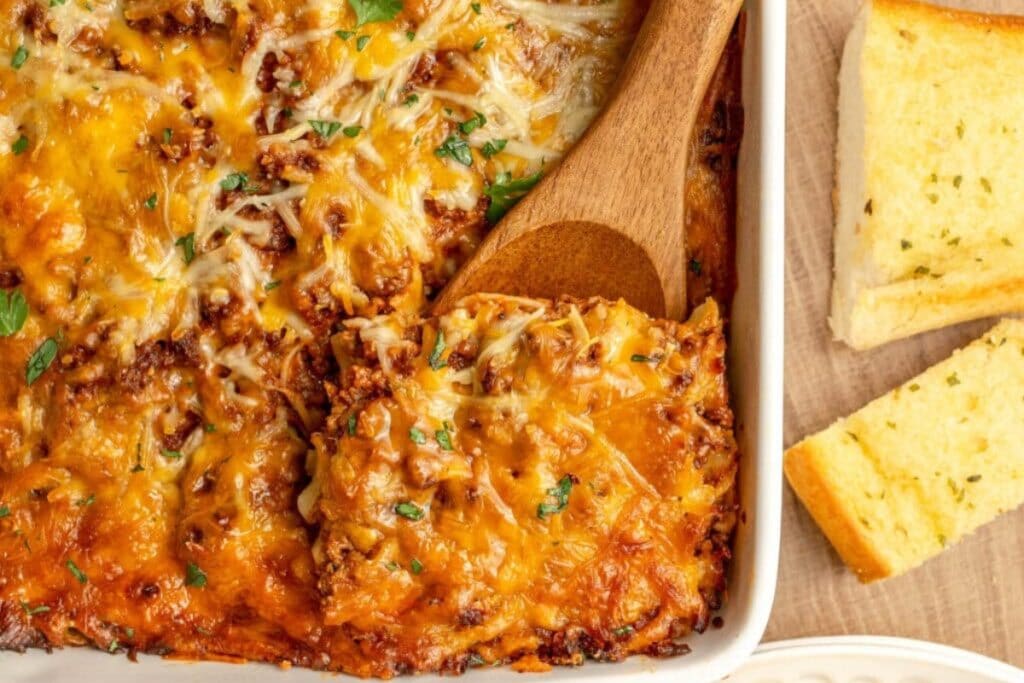Baked Italian noodle casserole with wooden spoon in a baking dish.