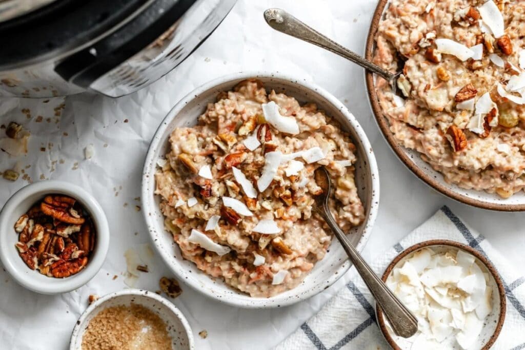 Overnight carrot cake oatmeal in bowls topped with nuts and coconut flakes.
