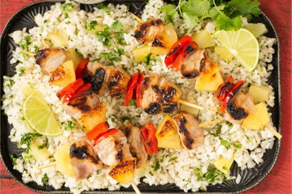 Pineapple pork kebabs on skewers served over rice.