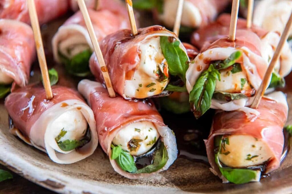 Prosciutto wrapped mozzarella bites on a plate.