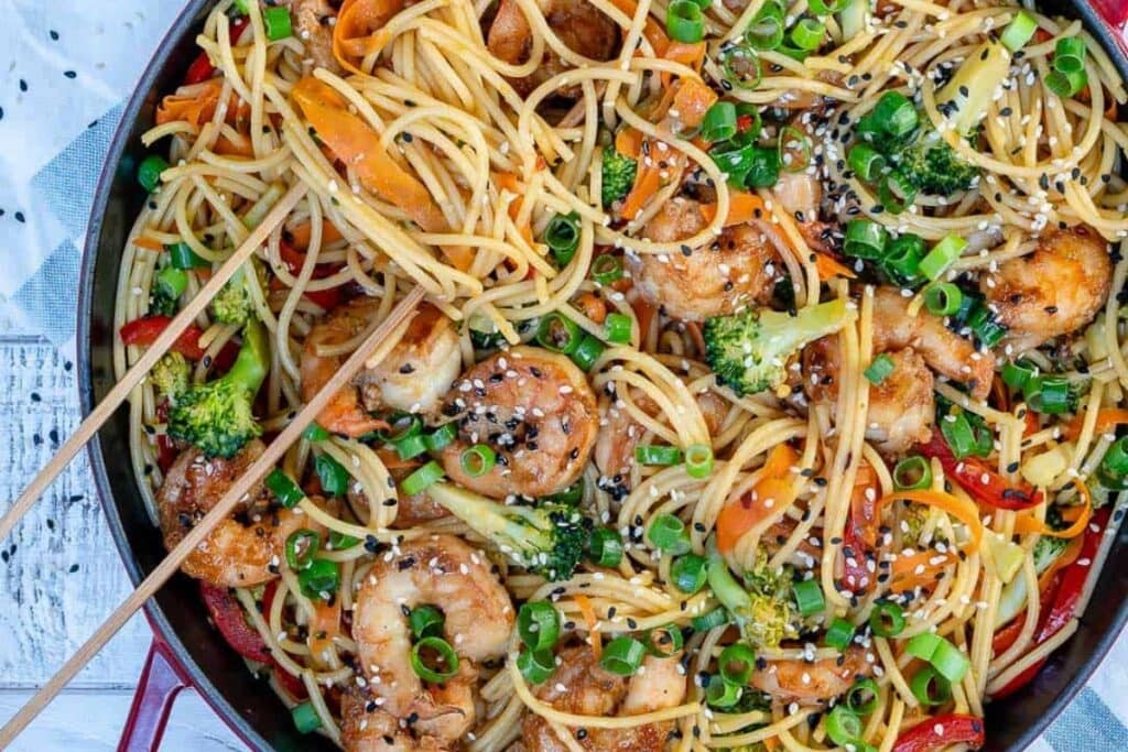 Shrimp stir fry noodles in a skillet.