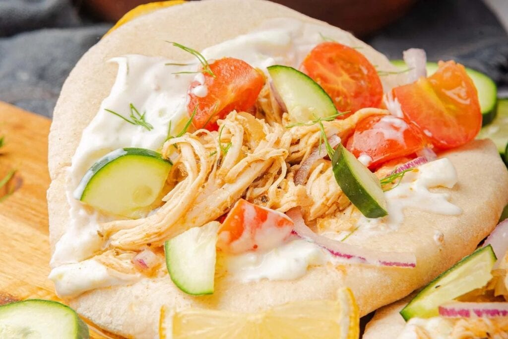 Slow cooker greek shredded chicken gyro on a wooden board.