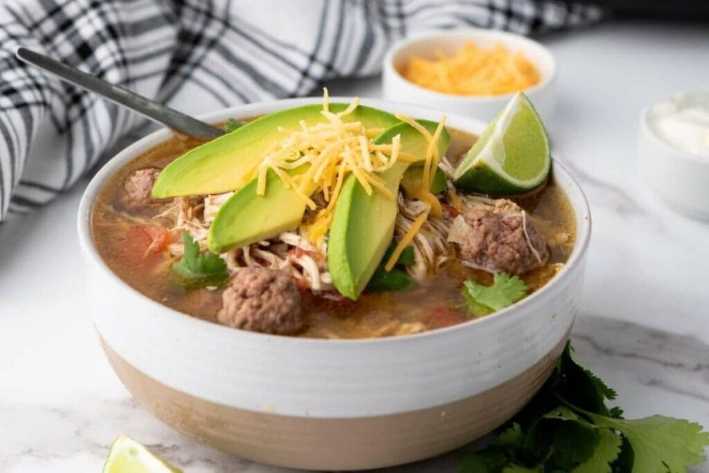 Slow cooker taco soup topped with sliced avocado in a bowl.