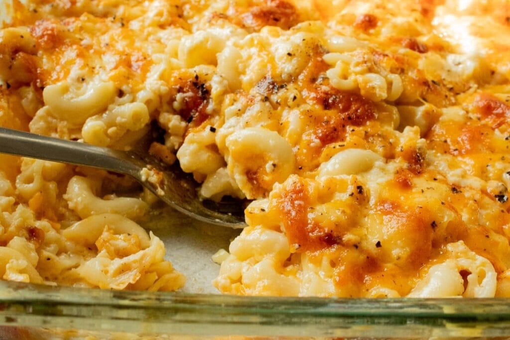 Close-up of southern baked mac and cheese in a glass dish with a spoon.