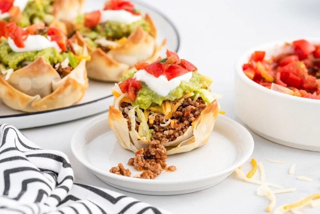 Mini taco bites with toppings on a plate.
