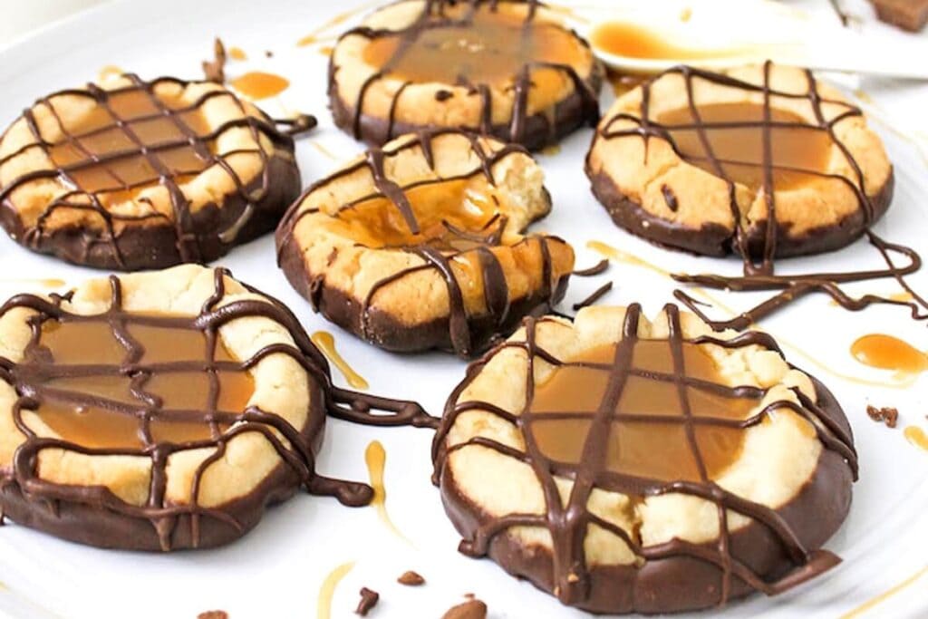 Twix cookies on parchment paper topped with caramel and chocolate.