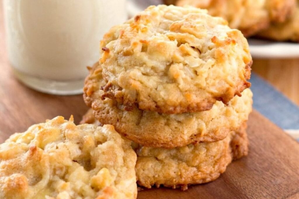 Stack of white chocolate macadamia coconut cookies on a wooden board.
