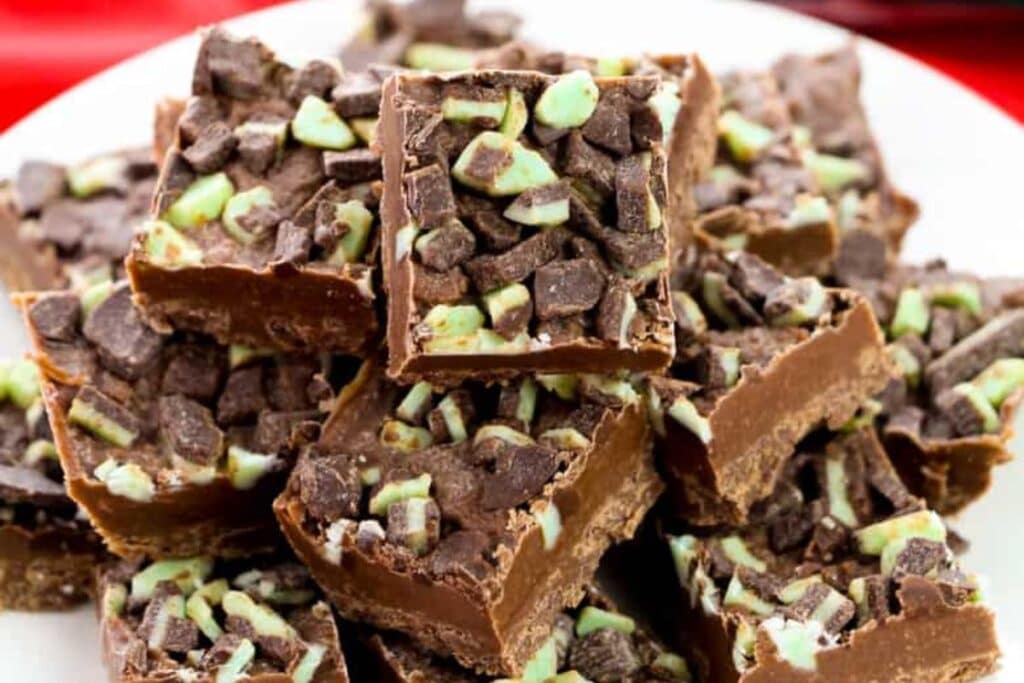 Pile of chocolate fudge squares with Andes mint pieces on a plate.