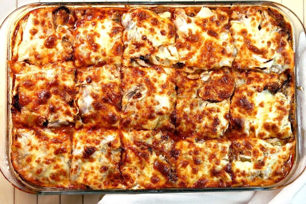 Overhead shot of cabbage lasagna with melted cheese in a glass baking dish.