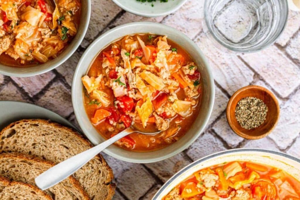 Cabbage roll soup with bread, pepper, and water.
