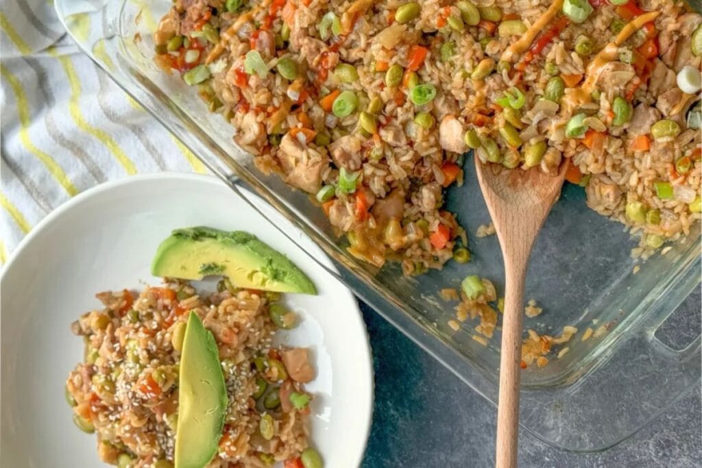 Chicken fried rice casserole in a glass baking dish and a bowl with avocado.
