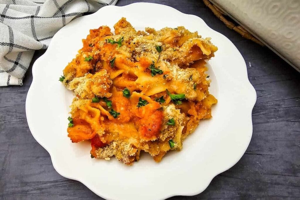Chicken parmesan pasta bake with breadcrumbs and parsley on a plate.