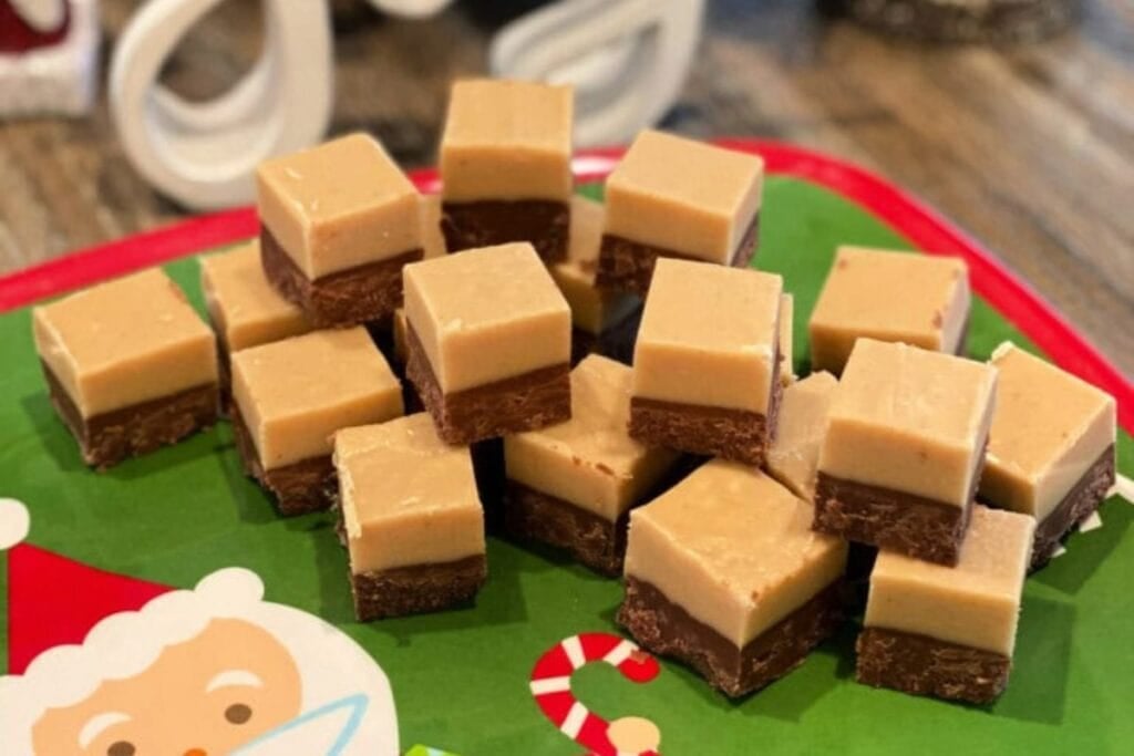 Two-layer chocolate peanut butter fudge squares on a Christmas plate.