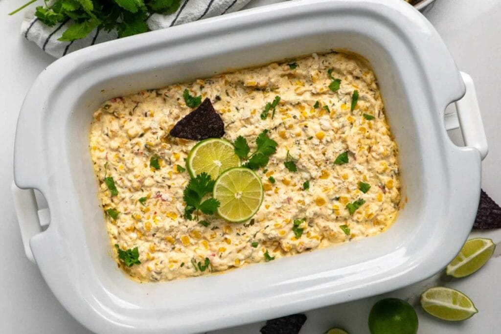 Crockpot Mexican street corn dip with lime and cilantro garnish.