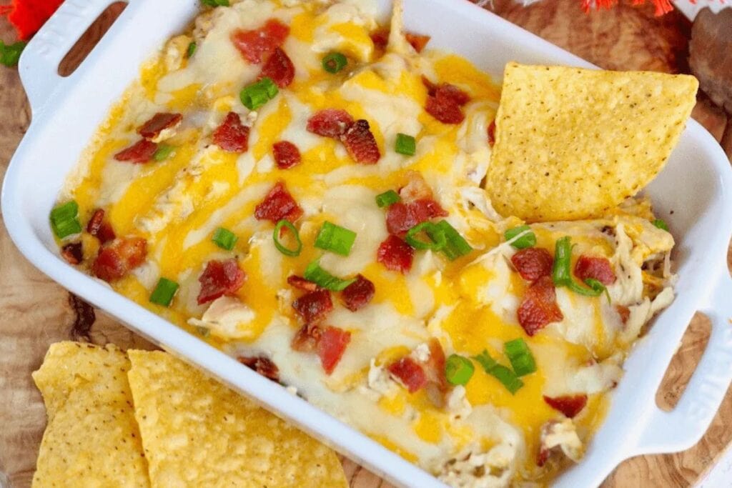 Chicken dip with melted cheese, bacon bits, and green onion garnish.