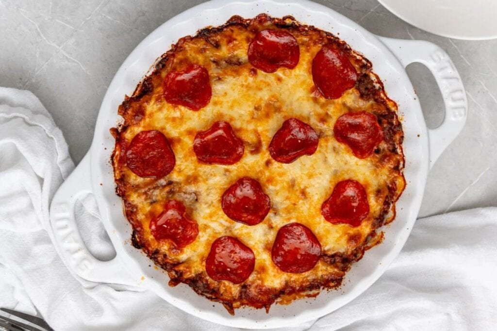 Overhead shot of a crustless pizza with pepperoni in a white dish.