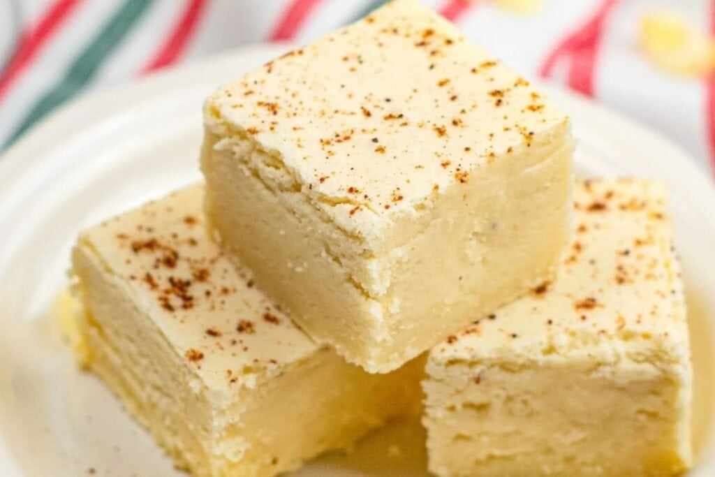 Stack of eggnog fudge squares with spice sprinkles on a white plate.