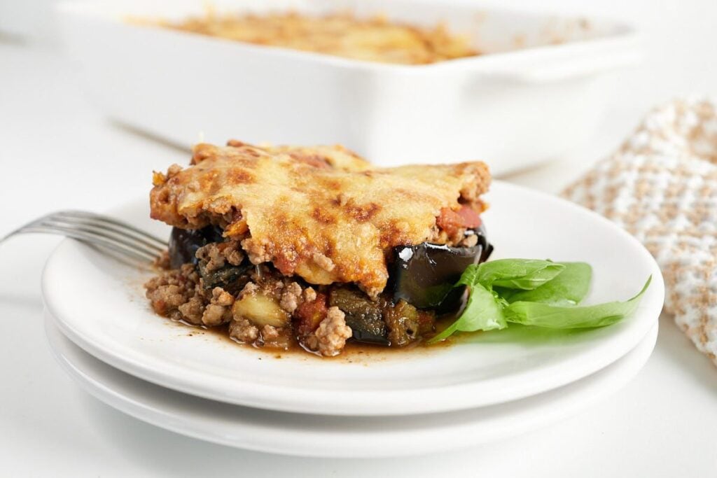 Slice of eggplant ground beef casserole on a plate with basil.