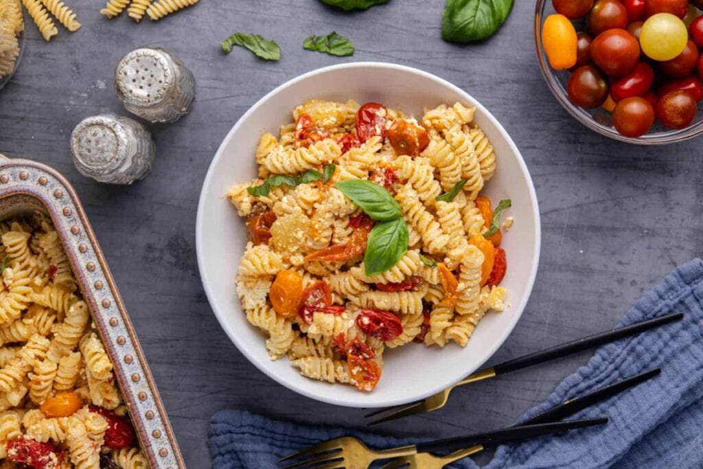 Baked feta pasta with tomatoes, basil, and rotini served in a bowl.