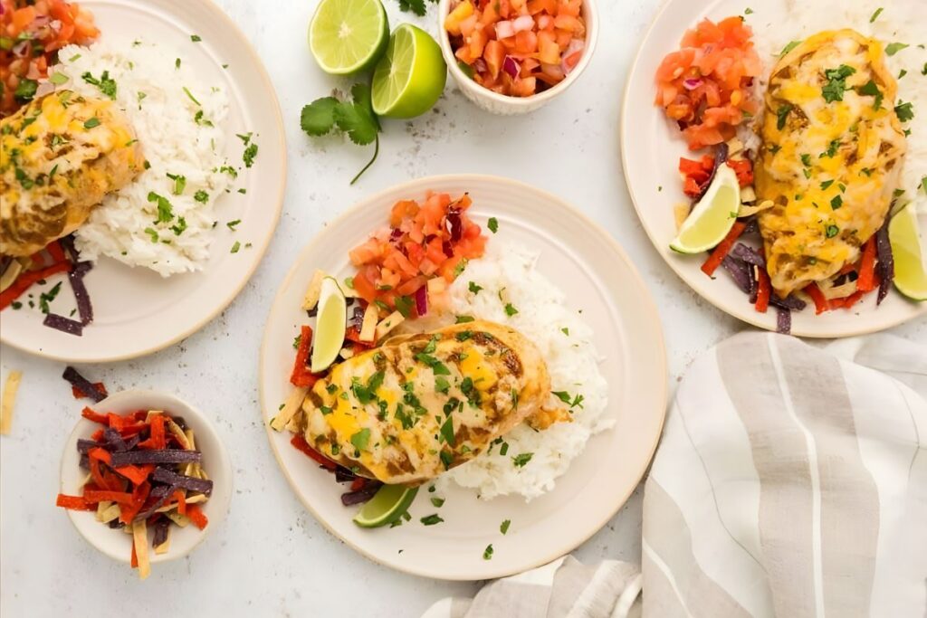 Three plates with chicken, rice, salsa, tortilla strips, and lime.
