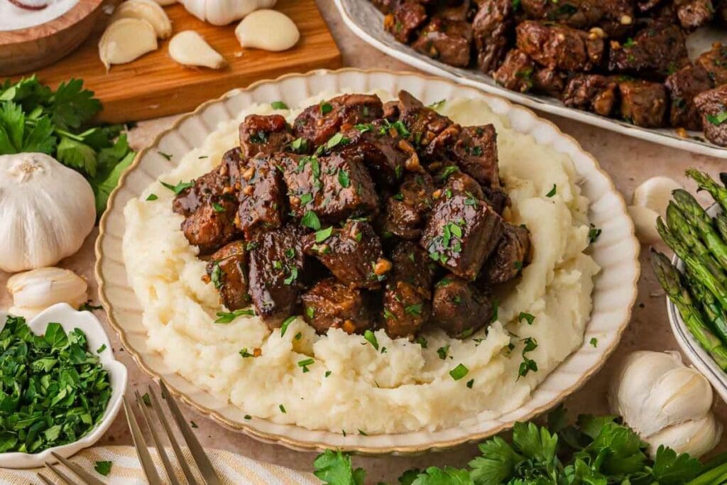 Garlic butter steak bites with mashed potatoes and asparagus on a plate.