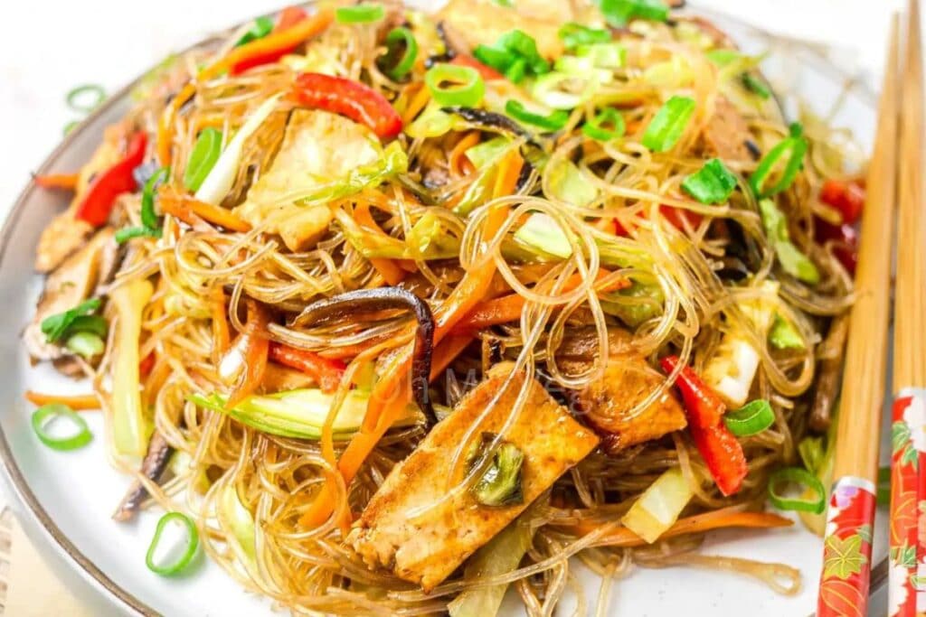 Close-up of glass noodle stir fry with tofu and colorful vegetables.