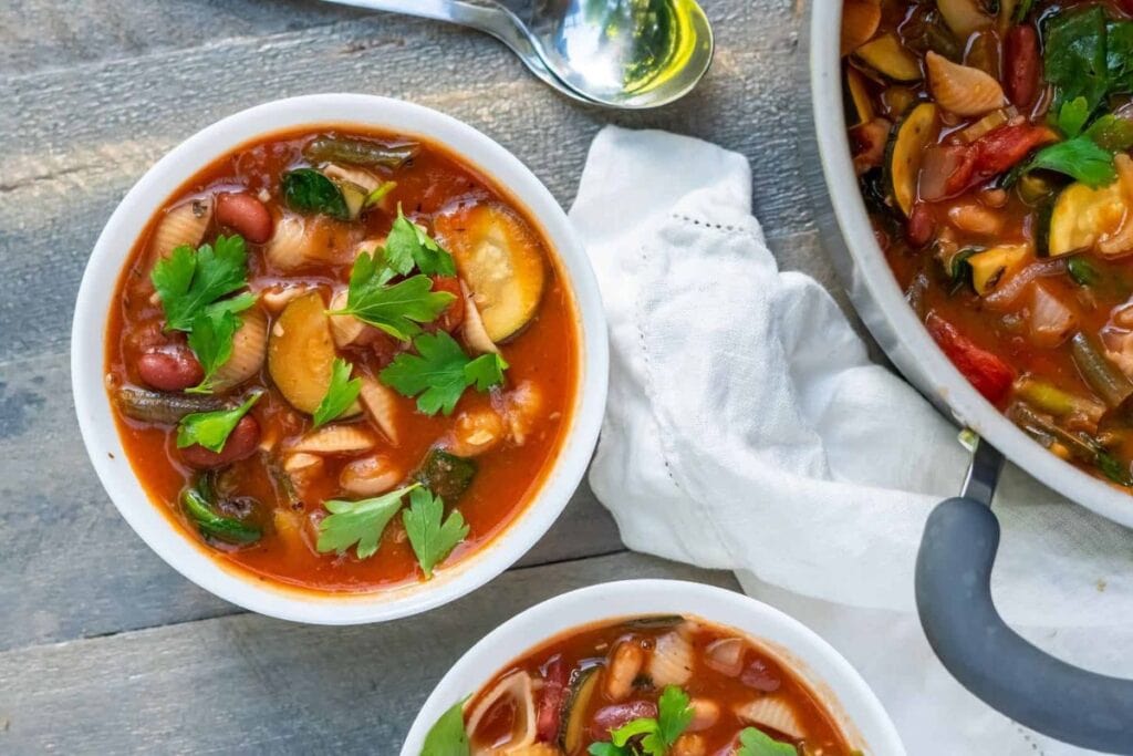Overhead shot of Italian minestrone soup with zucchini, beans, and parsley.
