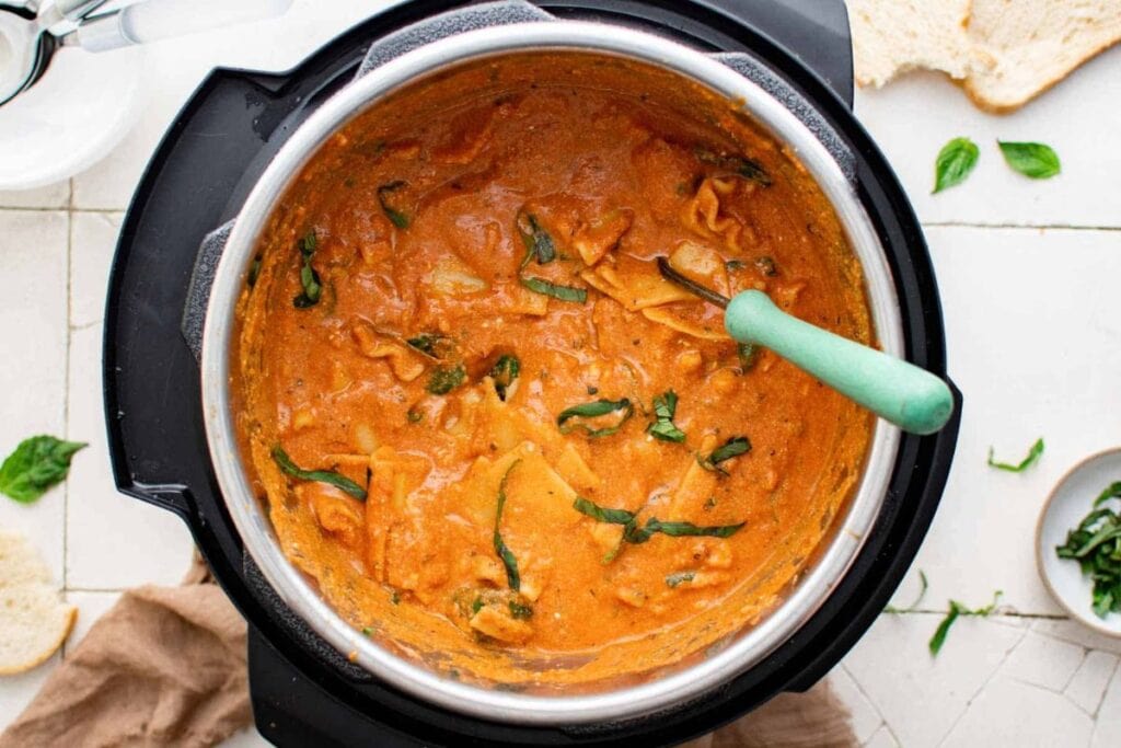 Lasagna soup in an Instant Pot with basil and a spoon.
