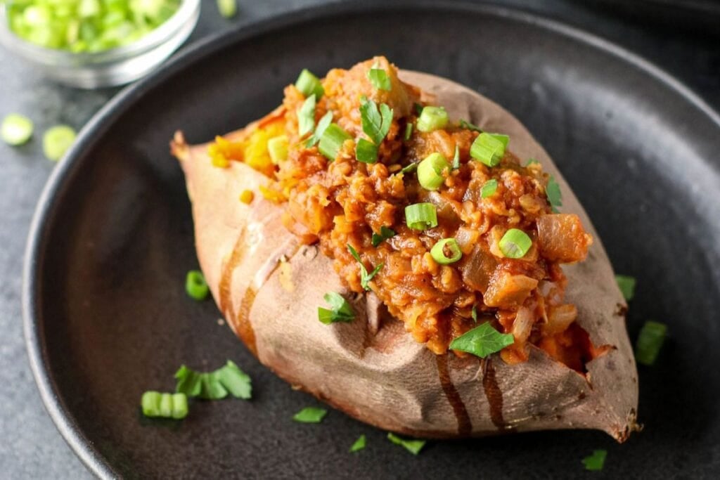 Close-up of lentil sloppy joe stuffed sweet potato with green onions.