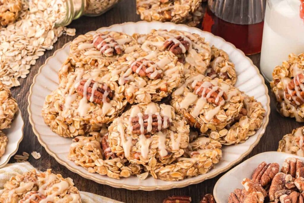 Plate of no-bake oatmeal cookies topped with pecans and maple glaze.