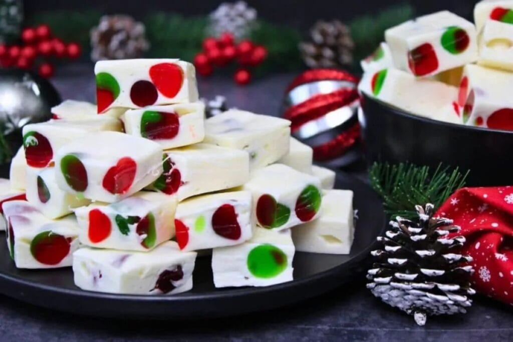 Marshmallow nougat candy pieces with red and green cherries and Christmas decorations.