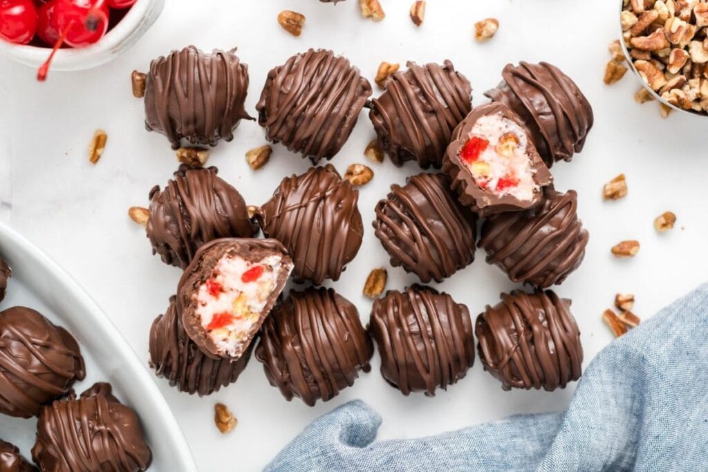 Chocolate-covered Martha Washington candies with cherries and pecans, some cut in half.
