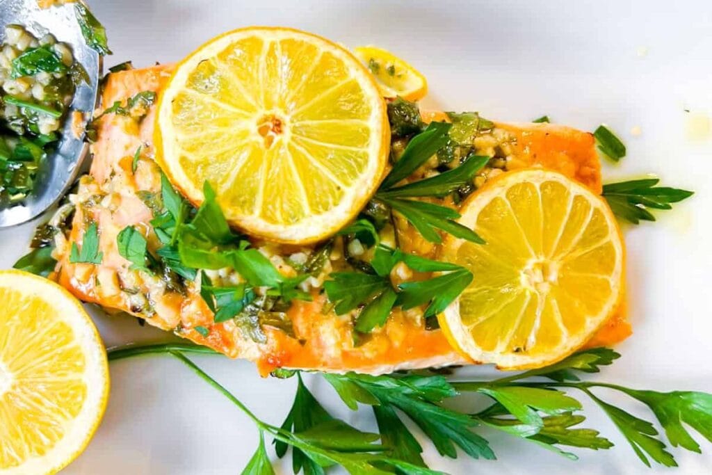 Salmon fillet topped with lemon slices, parsley, and couscous salad.