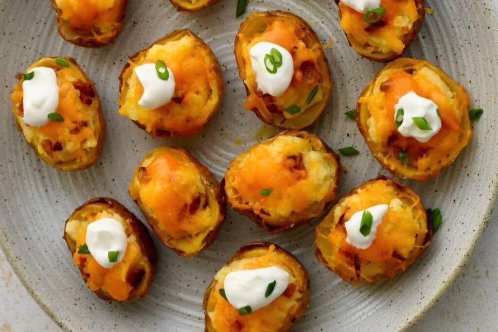 Potato skins filled with cheese, bacon, and sour cream on a plate.