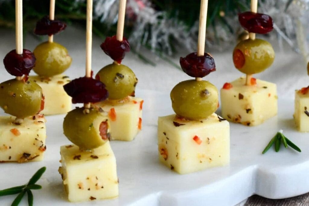 Olive, cheese, and cranberry skewers on a white serving platter.