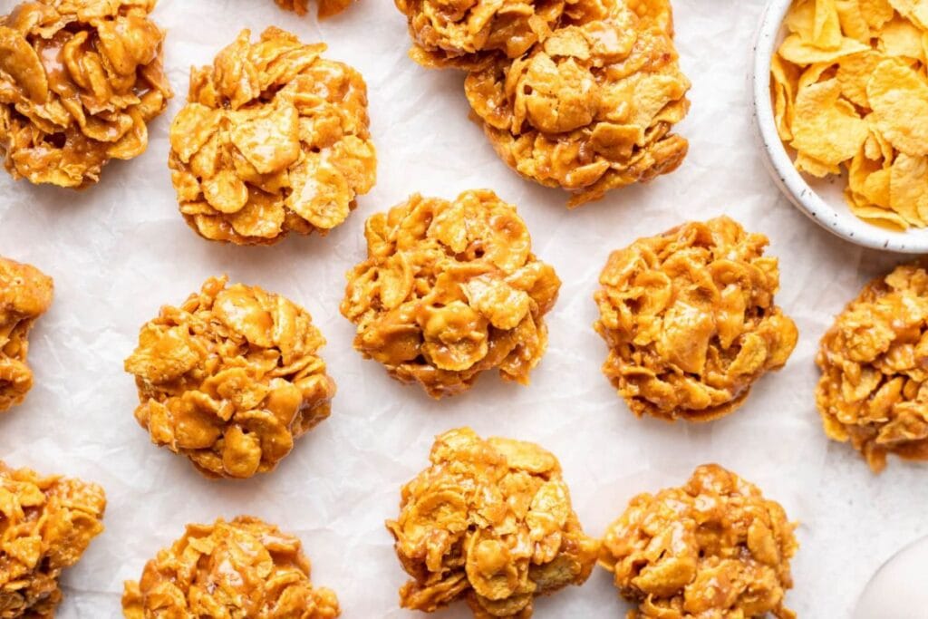 Overhead view of cornflake cookies with peanut butter on parchment paper.
