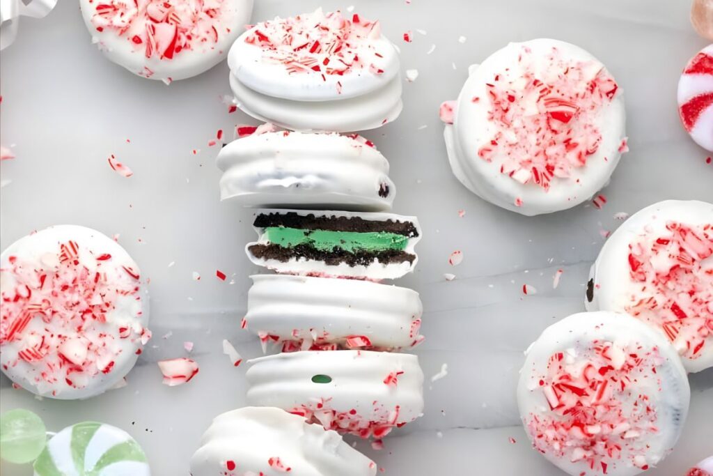 Overhead shot of white chocolate covered Oreos with peppermint sprinkles, one cut in half.